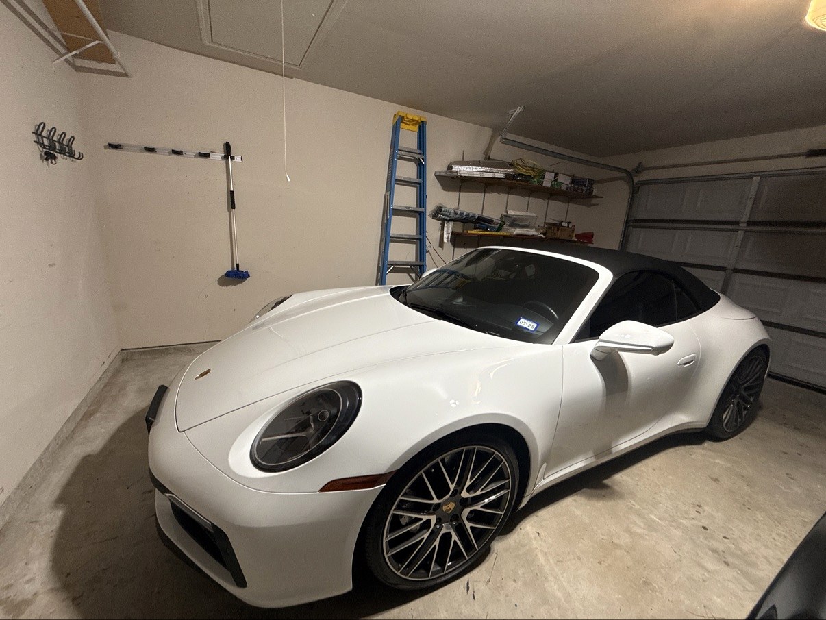 White Porsche 911 convertible with black soft top, front three-quarter view